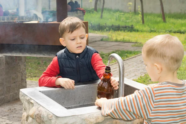 Two young boys filling a bottle of water
