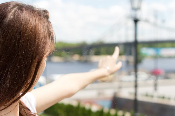 Female tourist pointing towards a remote bridge
