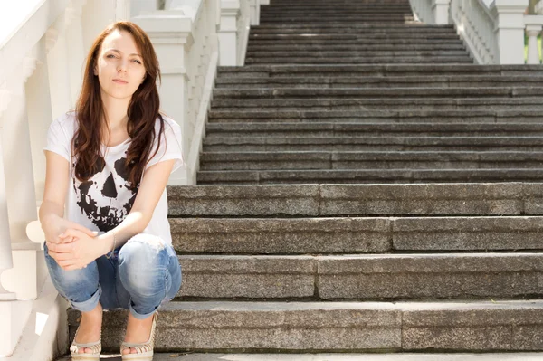 Lonely young woman sitting on a staircase
