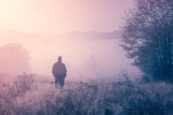 Lonely person in the morning mist. Landscape composition.