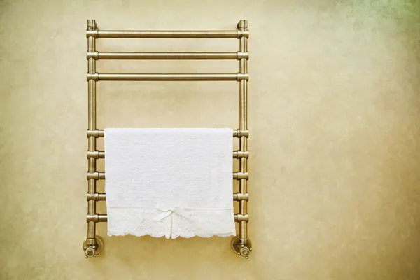 Modern heated towel rail on bathroom wall.