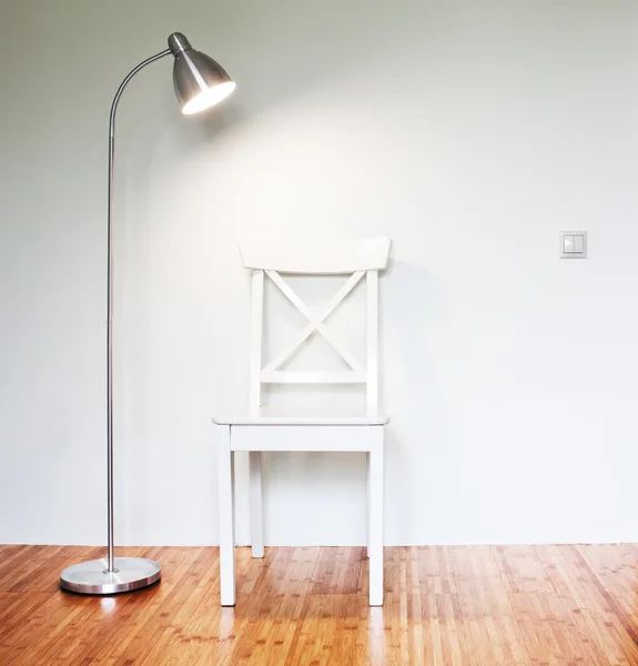 Wooden Chair with floor lamp to face a blank white wall