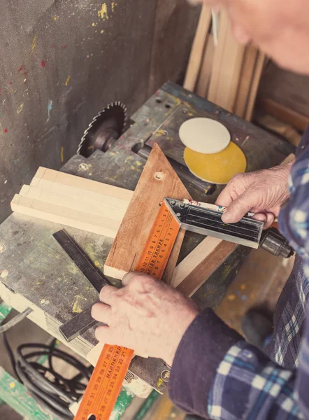 Old carpenter working with wood, retro tinted