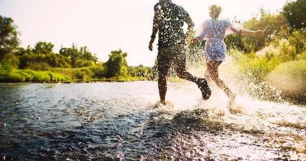 Happy couple running in shallow water. Summertime.