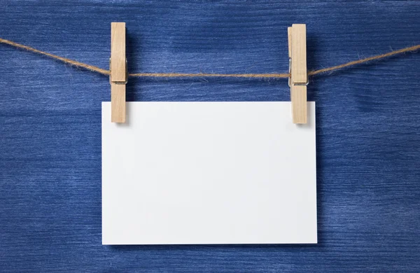 White blank paper card hanging over wood background