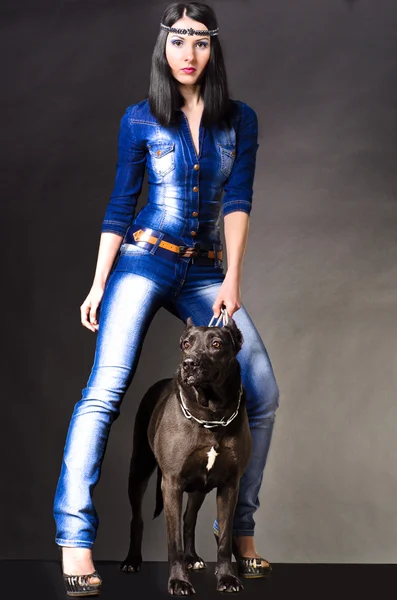Beautiful woman in jeans clothes standing next to a dog
