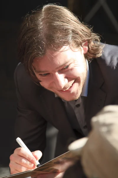 Martijn Smit smiling and signing a cd cover