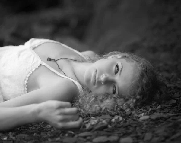 Beautiful woman laid down on the gravel.