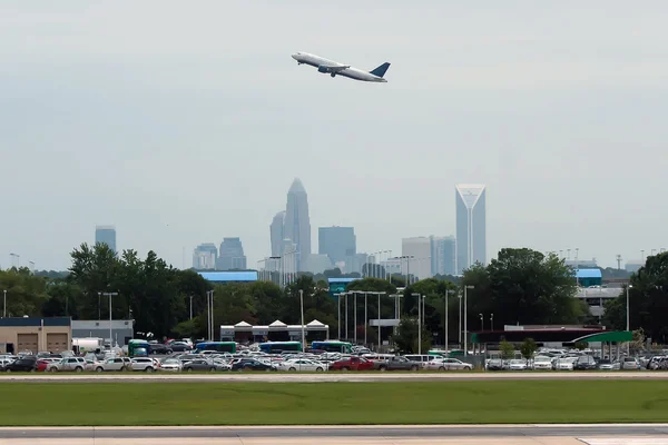 Commercial jet in the air with city skyline in the background.