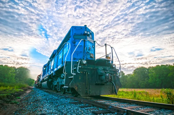 Blue freight train engine at sunrise