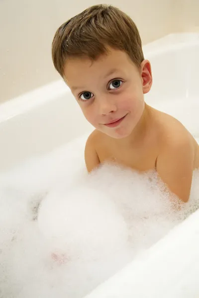 Cute three year old baby taking a bath with foam