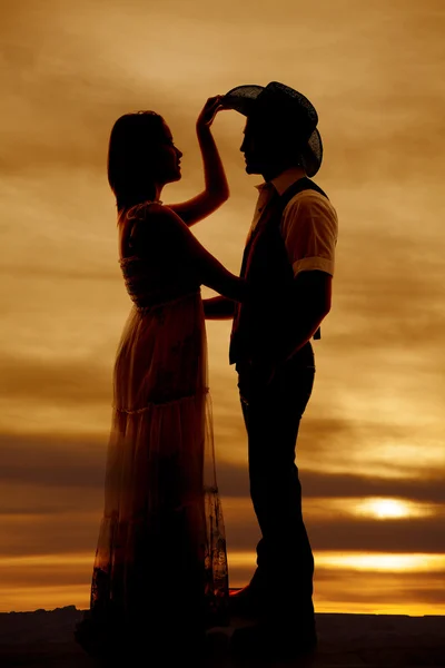 Cowboy couple silhouette her hand his hat