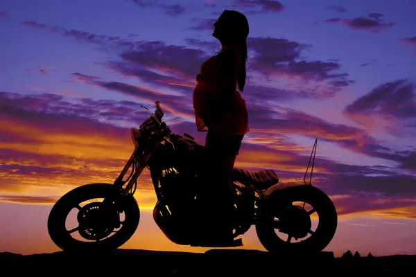Silhouette pregnant woman on motorcycle