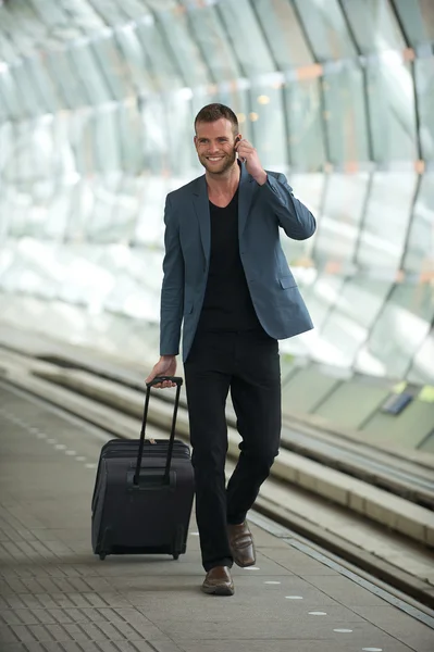 Young Caucasian Man Walking in City with Cell and Suitcase