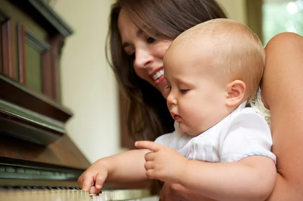 Beautiful woman teaching baby to play piano