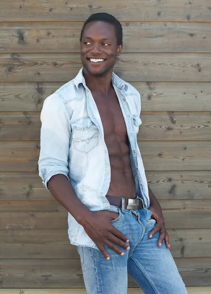 Happy young black man smiling outdoors with open shirt