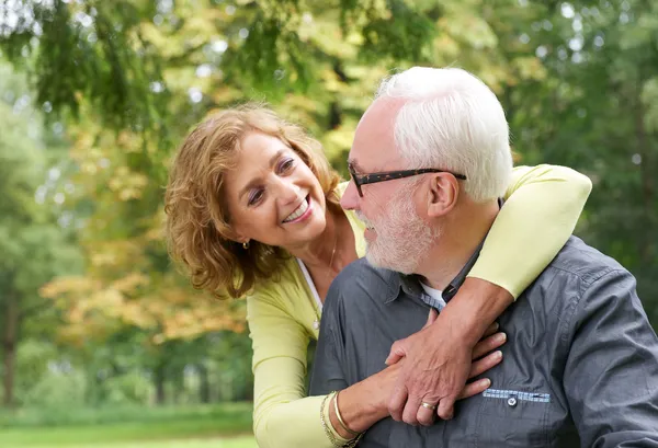 Happy older couple smiling and looking at each other outdoors