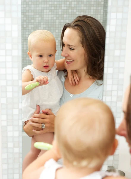 Happy mother holding cute baby with toothbrush