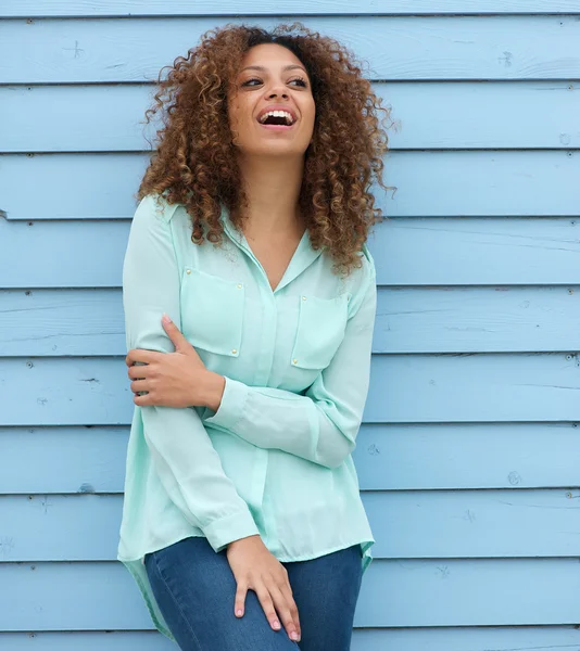 Young woman with curly hair standing outdoors and laughing