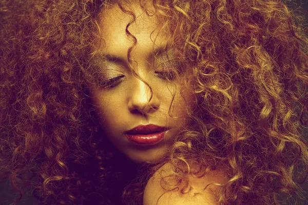 Young female fashion model with curly hair covering face