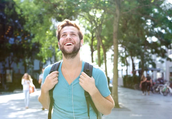 Handsome young man walking outdoors with backpack