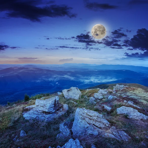 Light on stone mountain slope with forest at night