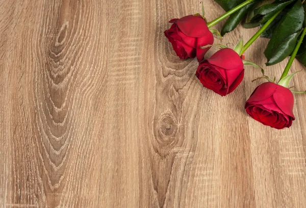 Three red roses on wood