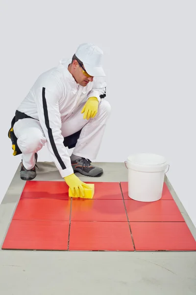 Worker with yellow gloves and sponge clean red tiles