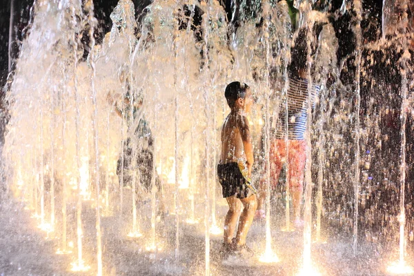 Three Kids playing in water fountains