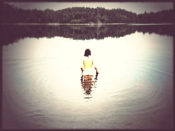 Vintage style image of nude woman in dark lake