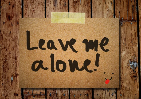 Note paper and clothes peg on a wooden background with leave me