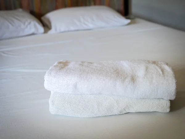 Stacked white spa towels on bed