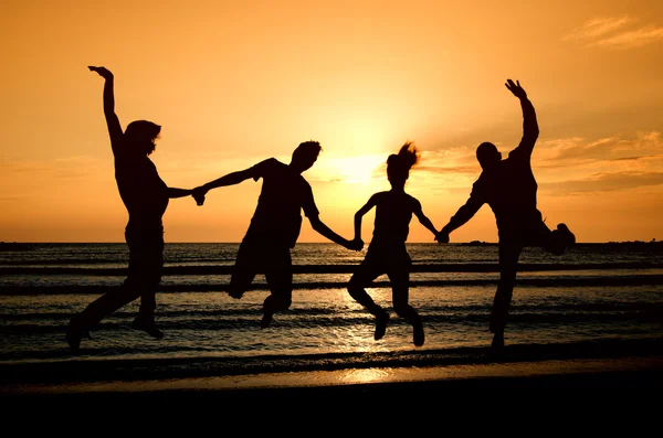 Group of happy parting on the beach at sunrise