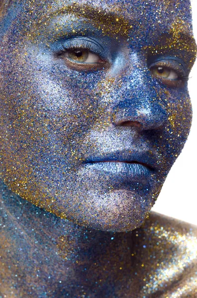 Beautiful face of a woman covered in glitter Close up of a woman's face covered in blue and purple glitter