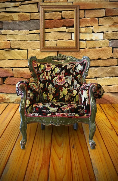 Antique armchair in the brick wall room with a frame hanging on.