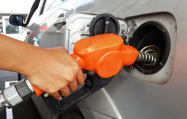 Woman hand refilling gas to car with fuel on a filling station.