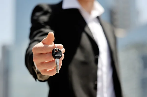 Businessman holding a car key in his hand - new car buy sale concept