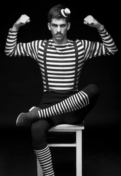 Morose circus performer sitting in a striped dress