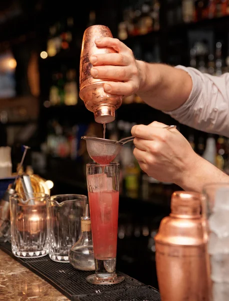 Bartender is straining cocktail