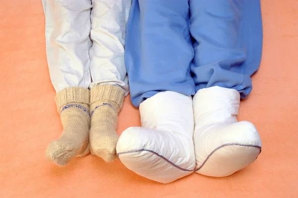 Two Couple's feet warming at a bed