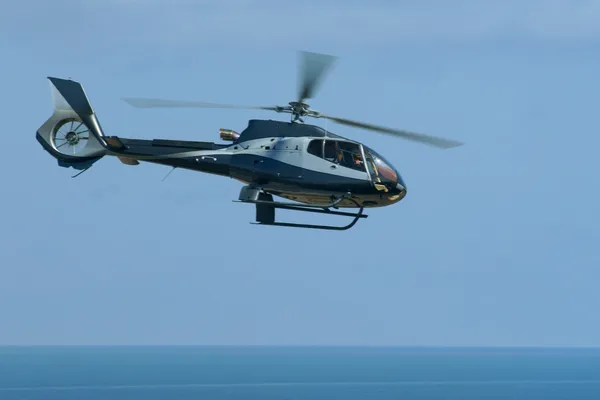 Helicopter flying on blue sky and sea