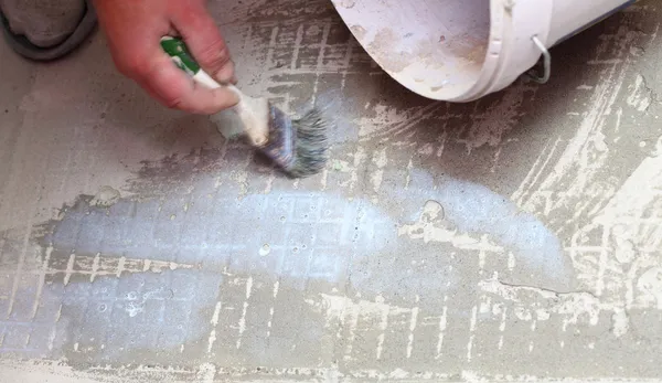 Construction brush worker is tiling at home tile floor adhesive