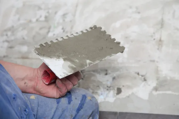 Construction worker is tiling at home tile floor adhesive