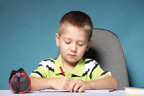 Young cute boy draws with color pencils