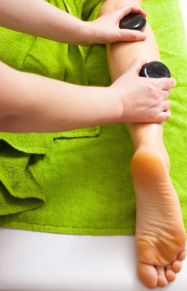 Beauty salon. Woman getting spa hot stone legs massage
