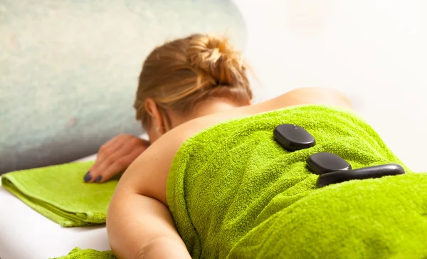Spa salon. Woman relaxing having hot stone massage. Bodycare.