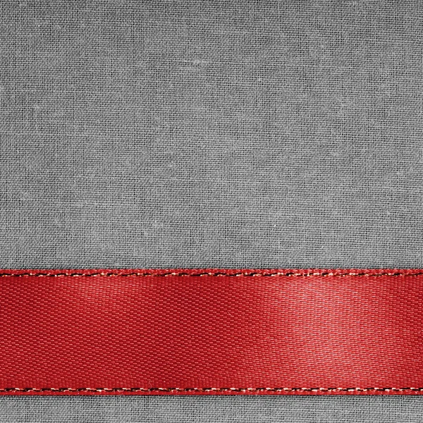 Red ribbon on gray fabric background with copy space.