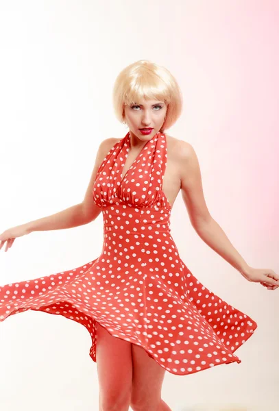 Beautiful pinup girl in blond wig and retro red dress dancing. Party.