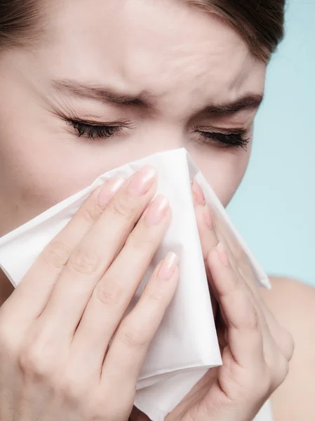 Sick girl sneezing in tissue.