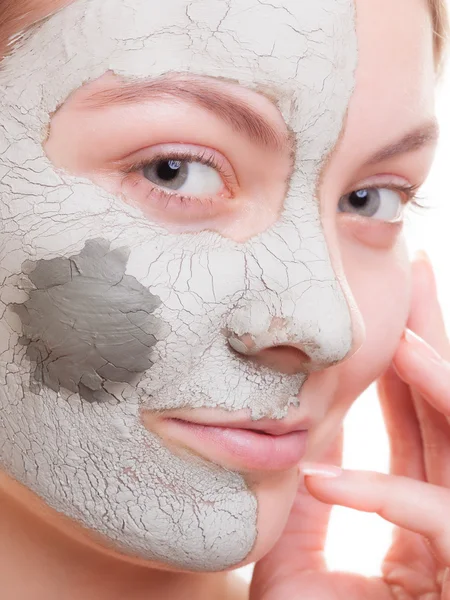 Woman applying clay mask on face. Spa.